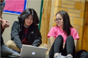 Two students look at a laptop