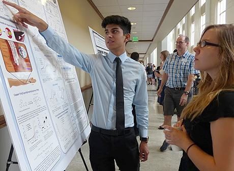 Student presenting poster to a peer