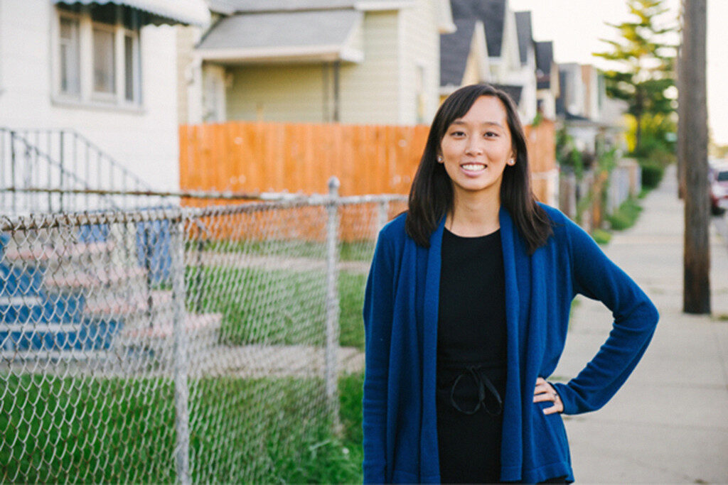 Stephanie Gray Chang poses in front of a row of houses.