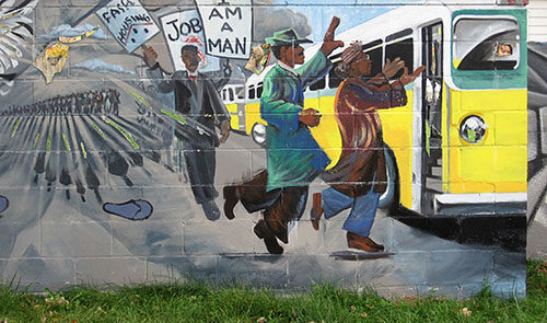 Mural depicting line of people getting on a bus, with some of the line holding signs.