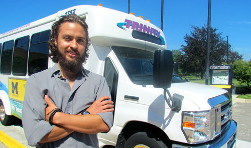 Student poses in front of shuttle bus.